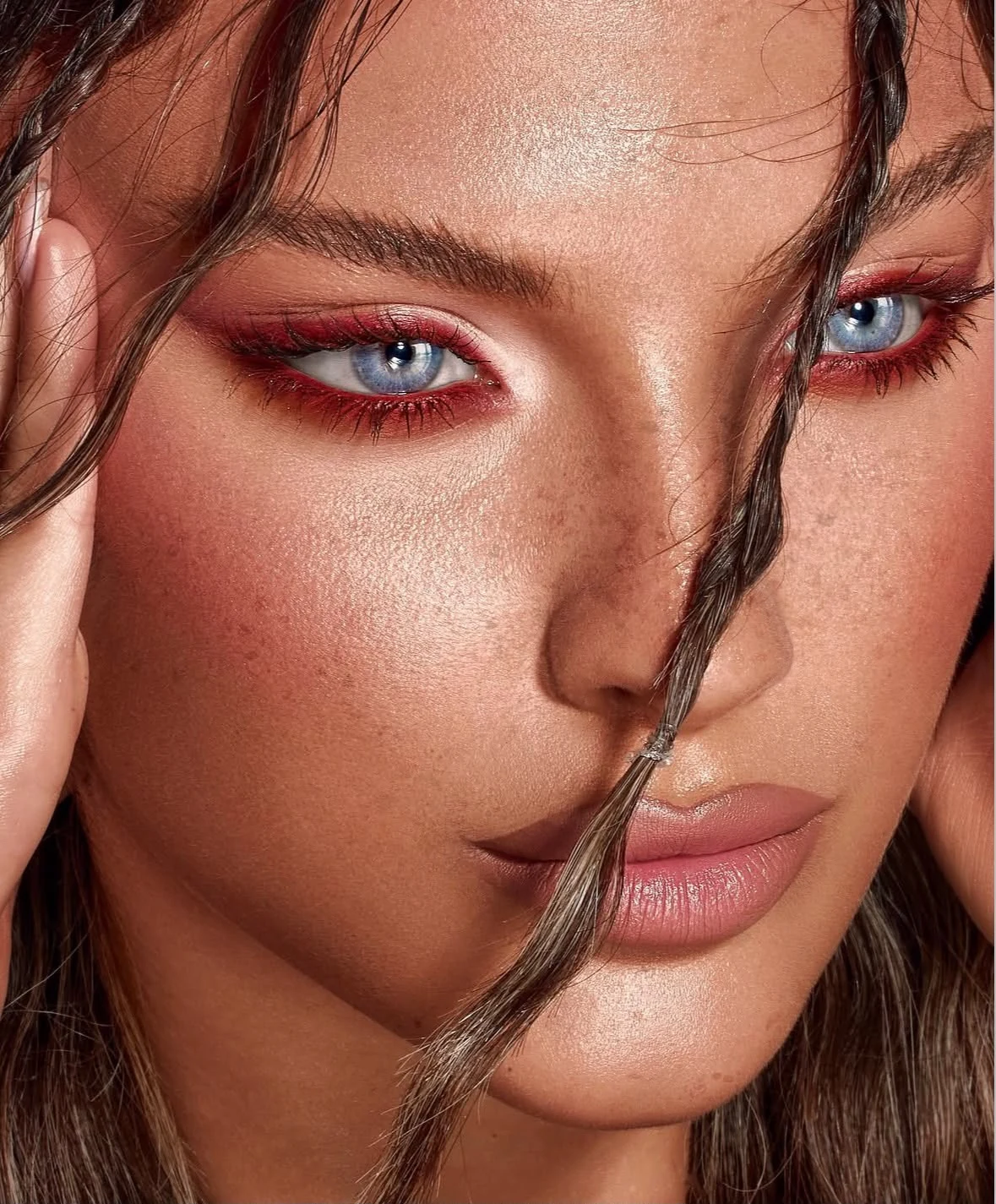 A close-up of vivid crimson eyeshadow and softly luminous skin.