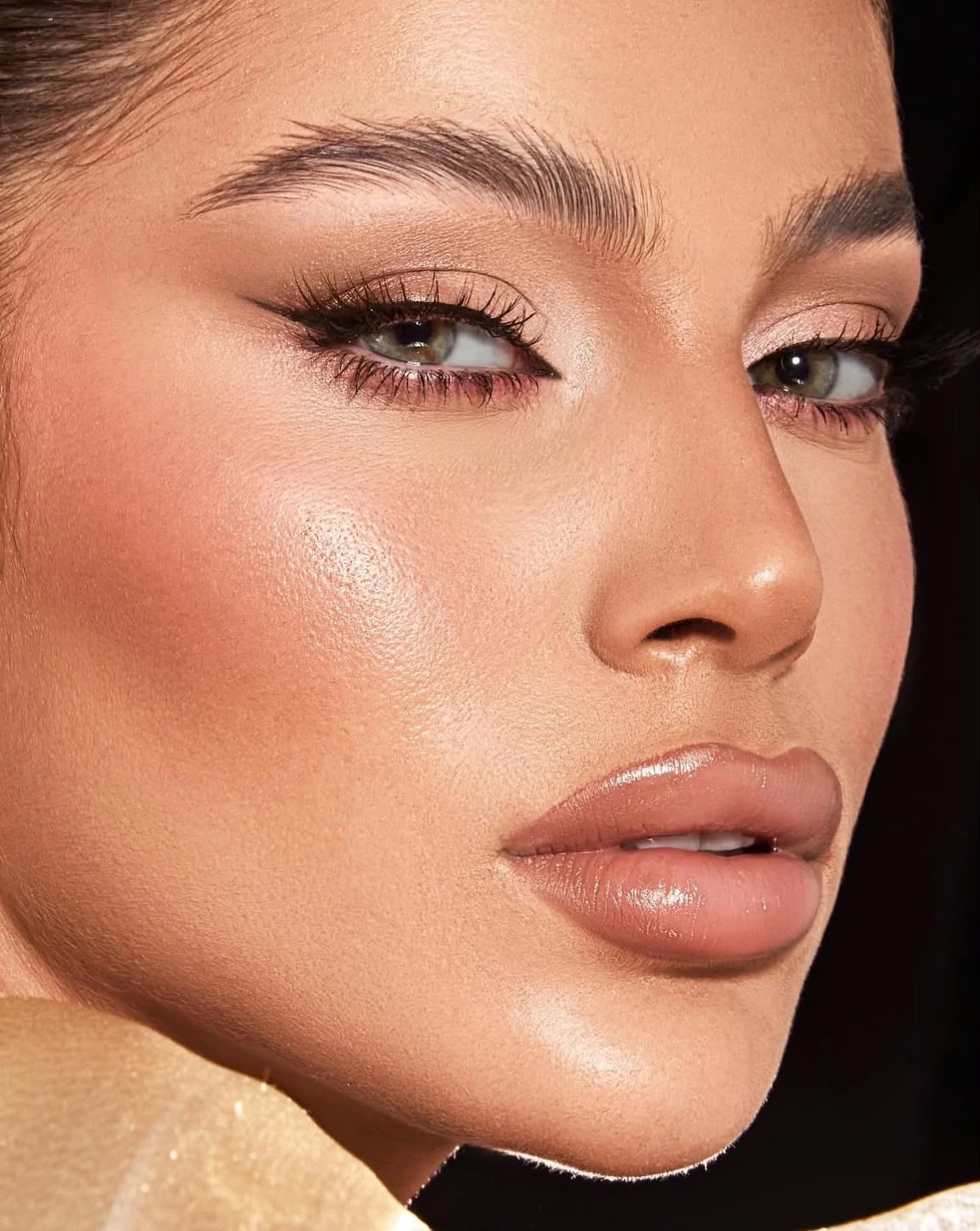 A close-up of softly defined eyes and a glossy nude finish.